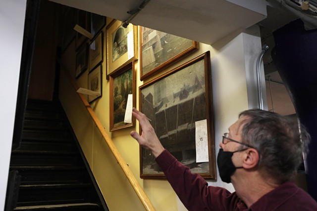 Rochester Historical Society archivist Bill Keeler found some wall space to hang paintings of Rochester in a stairway leading to the basement in the organization's new space. - PHOTO BY MAX SCHULTE