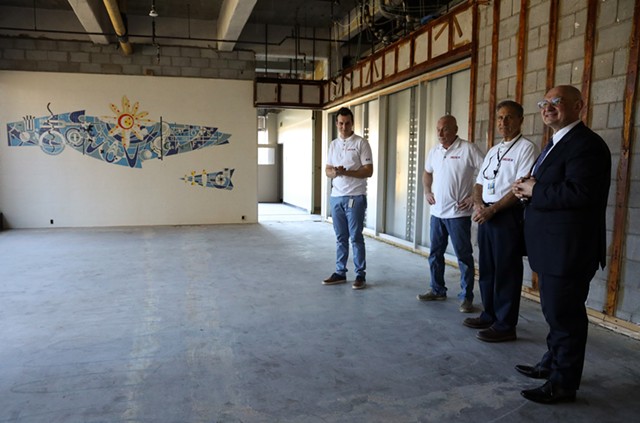 Delta-X employees from left, Mark Douglas, rehab project manager; Joe Shufelt, facilities manager; John Picardo, facilities engineer, and Derek Dlugosh-Ostap, the company's CEO, stand before the mural uncovered in the former Kodak building they are rehabbing. - PHOTO BY MAX SCHULTE
