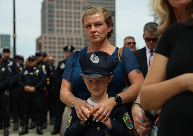 Megan Millspaugh and her son, Macsen, watch the presentation of the flag to Rochester Police Officer Anthony Mazurkiewicz's family after his funeral. Millspaugh's husband is a Rochester police officer. - PHOTO BY MAX SCHULTE